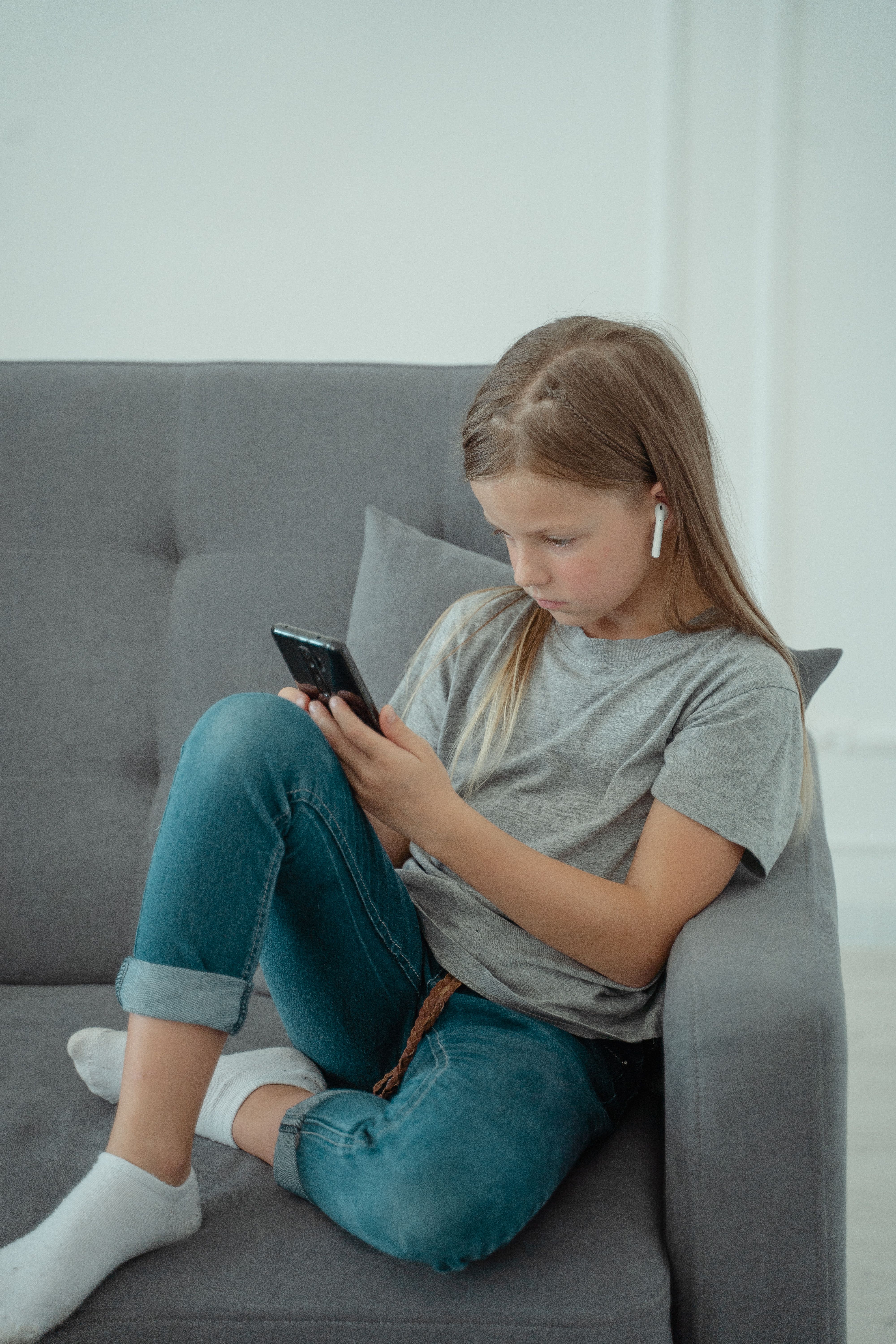 A child sitting on a sofa and looking at a phone