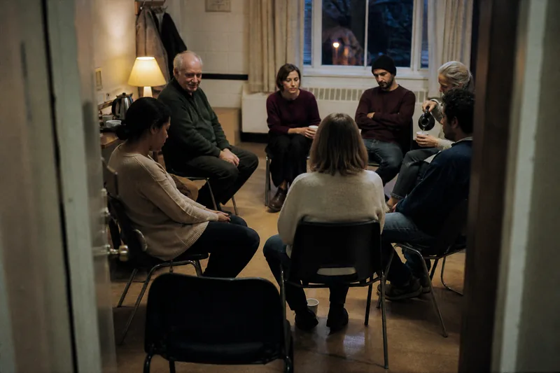An ordinary peer-support meeting seen through a half-open doorway