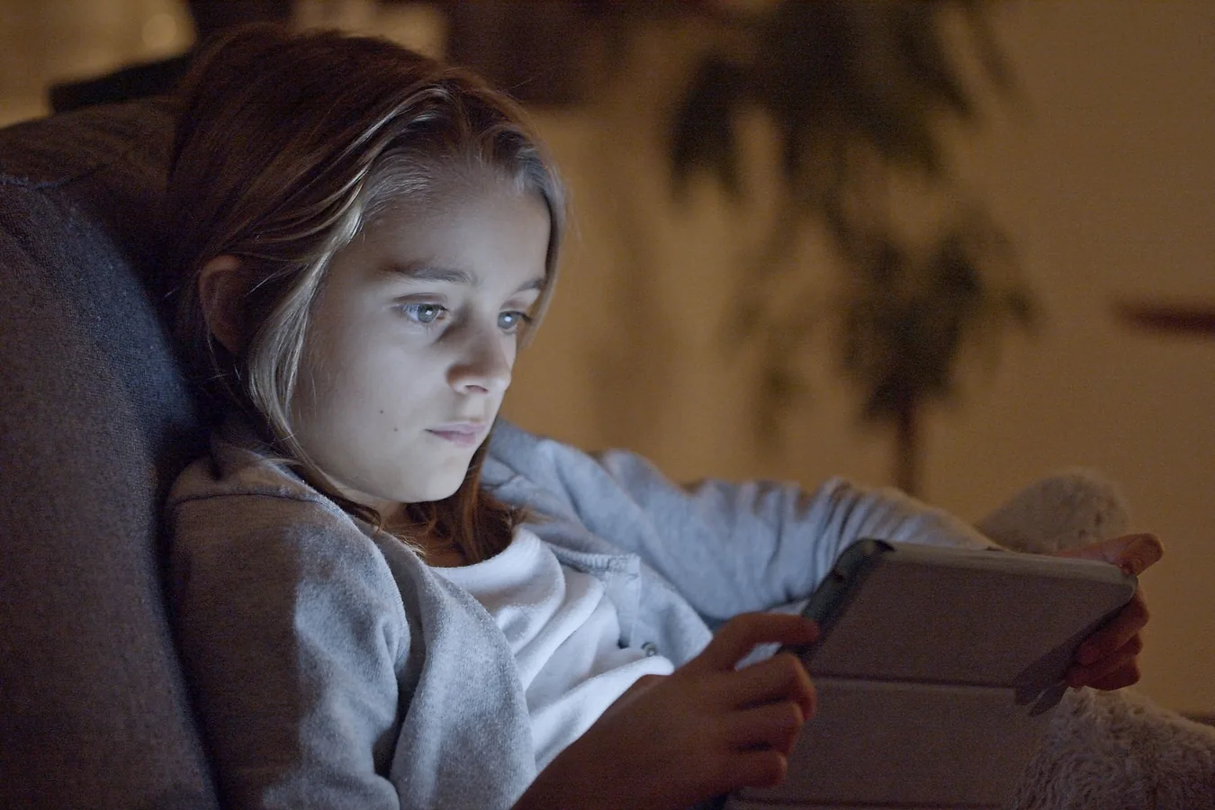 A child using a tablet while sitting on a sofa