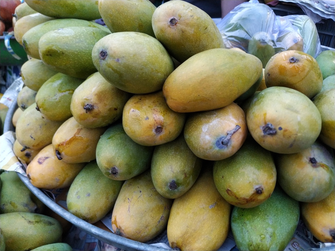 A pile of yellow and green Dasheri mangoes at a market
