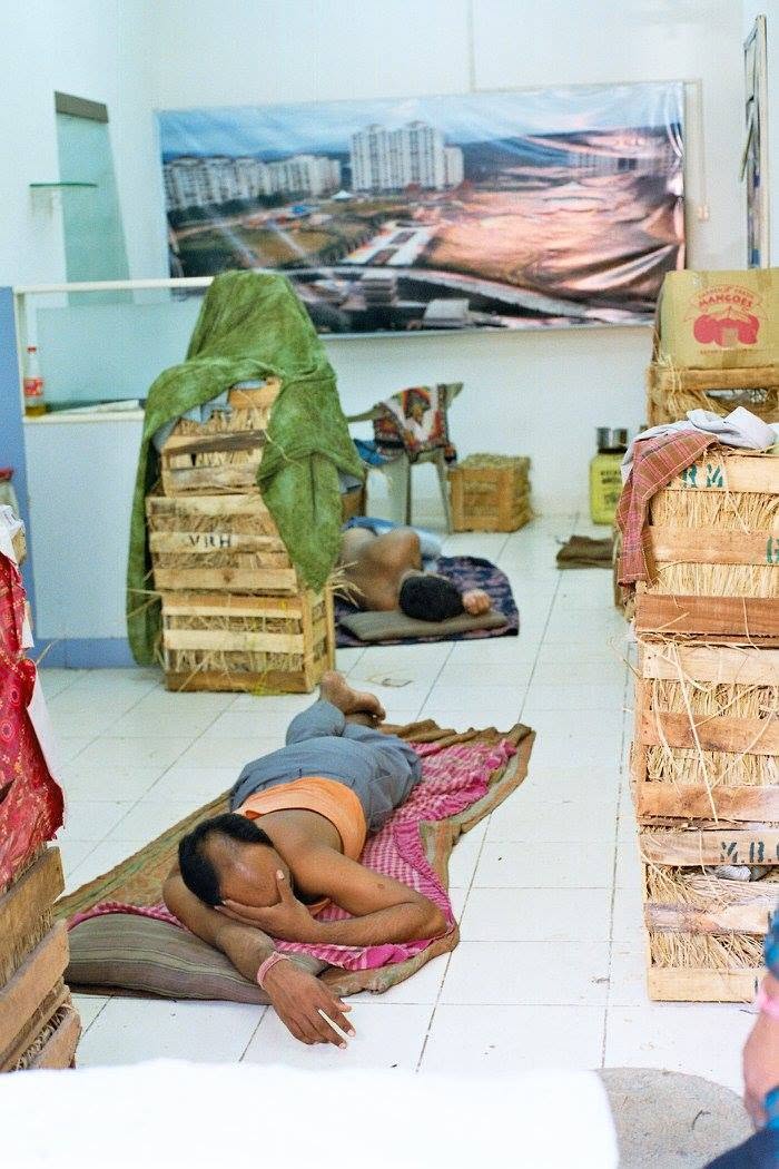 Two mango sellers sleeping on mats among tall stacks of mango crates