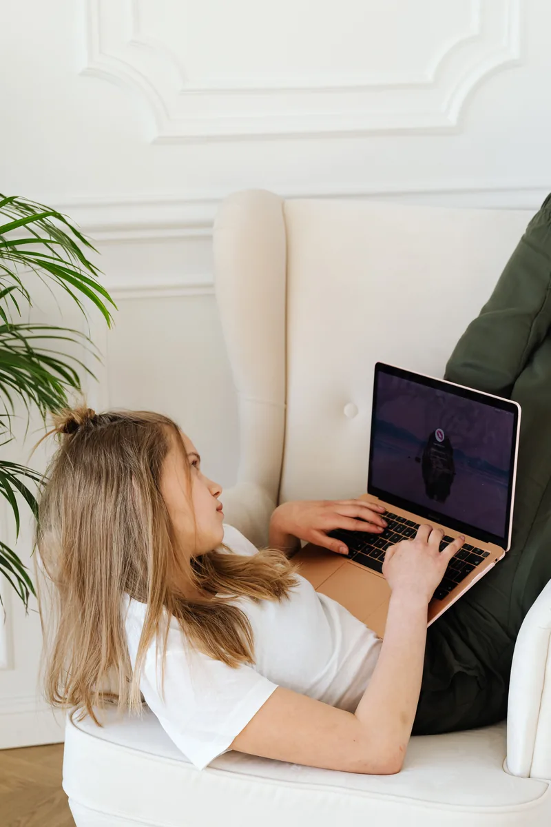 A teenager using a laptop in a bright living room
