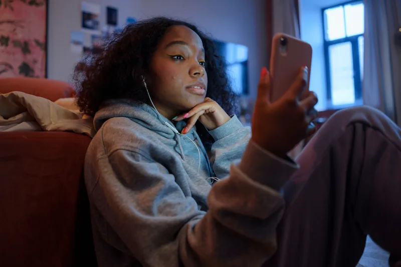 A teenage girl listening through earphones while using a tablet