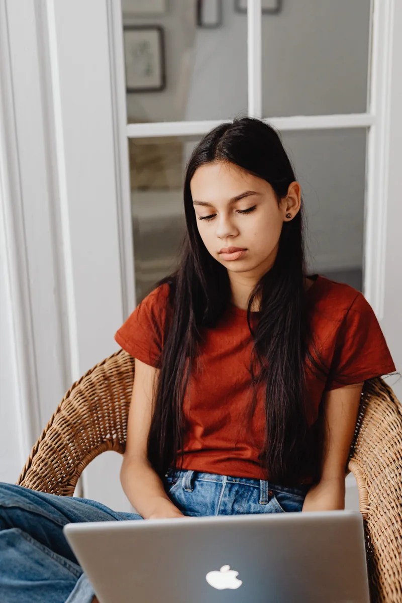 A teenage girl looking down at a laptop