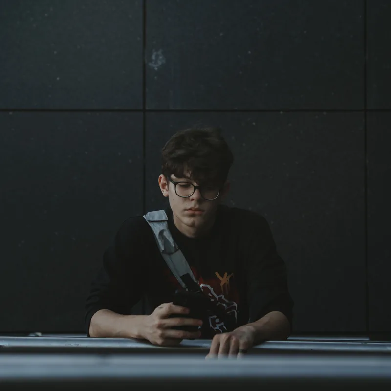 A teenage boy checking a phone alone