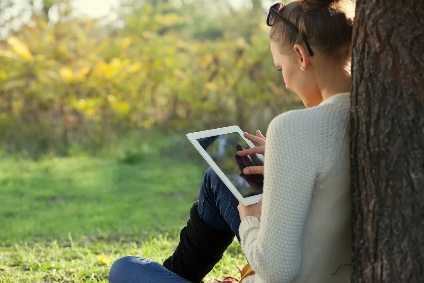 A young person using a tablet while sitting outside