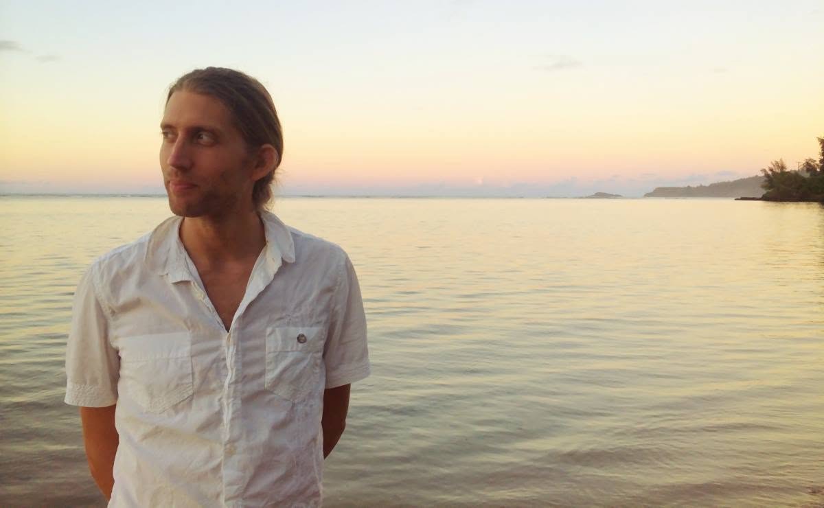 Michael Mackintosh standing beside the sea at sunset