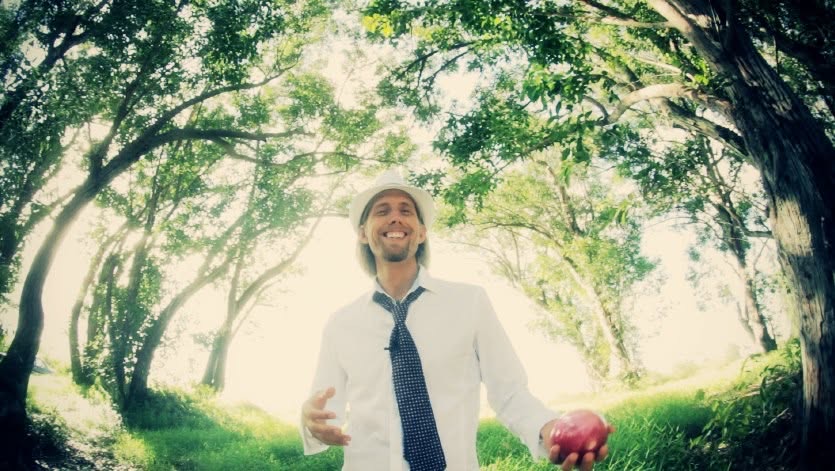 Michael Mackintosh holding an apple beneath the trees