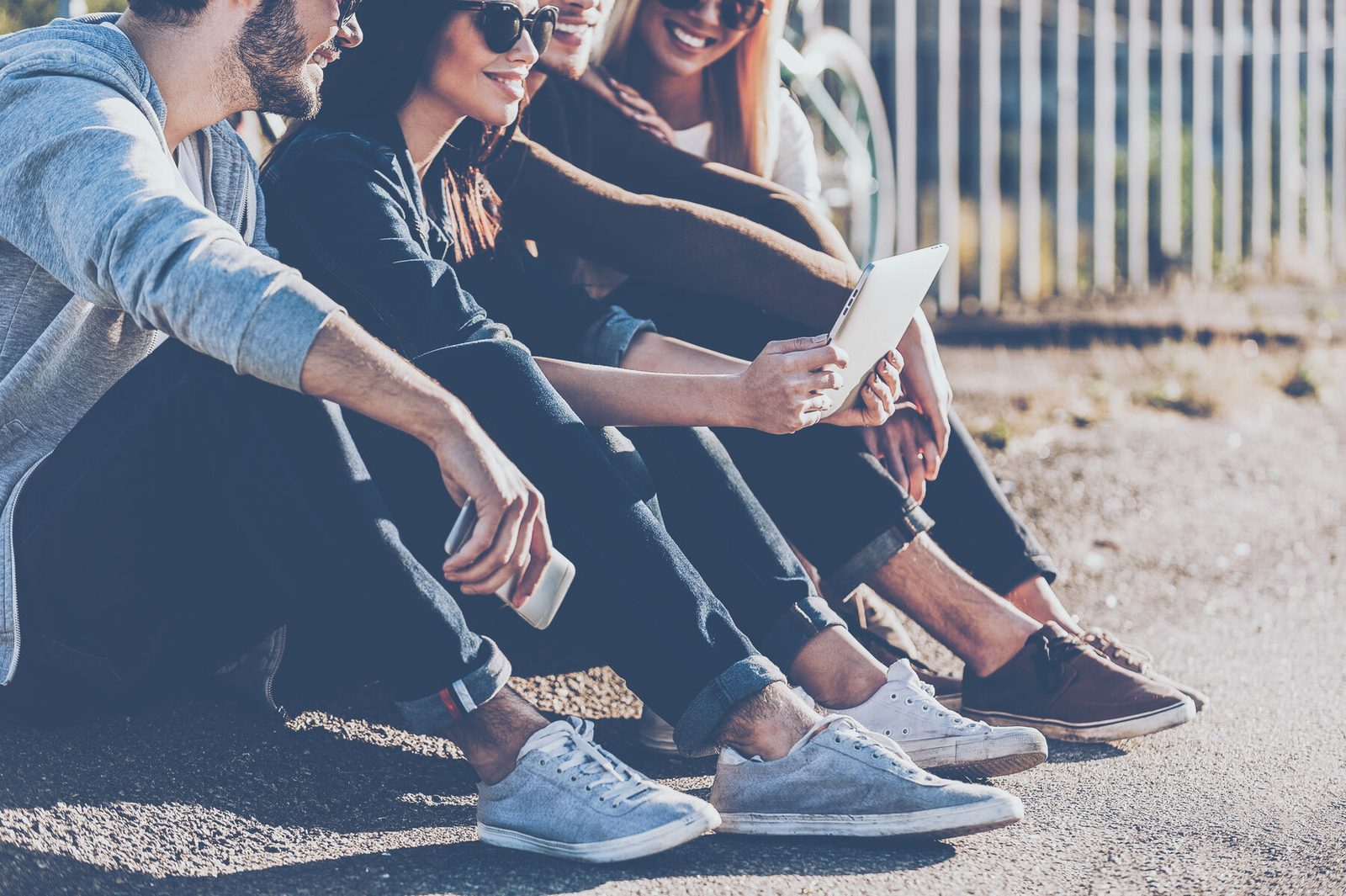 A row of young people sitting together, every one looking at a phone
