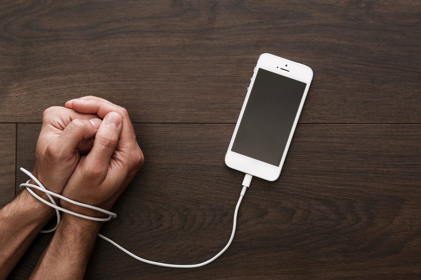 Hands bound together with a phone charging cable
