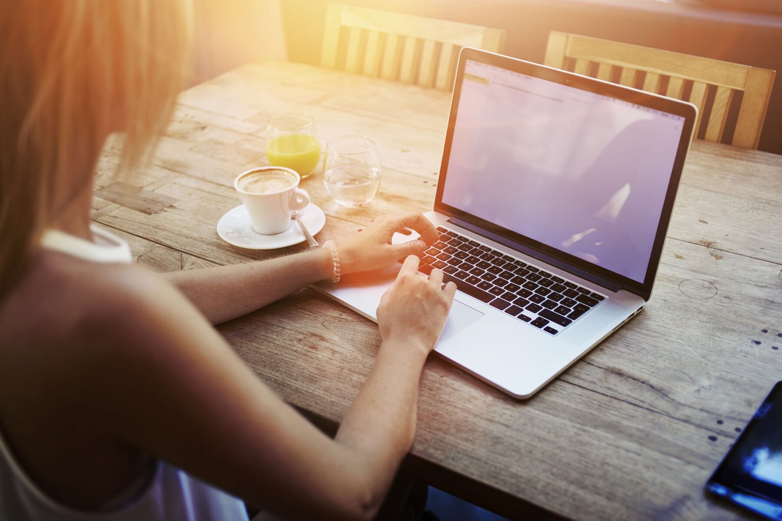 A person using a laptop at a sunlit table