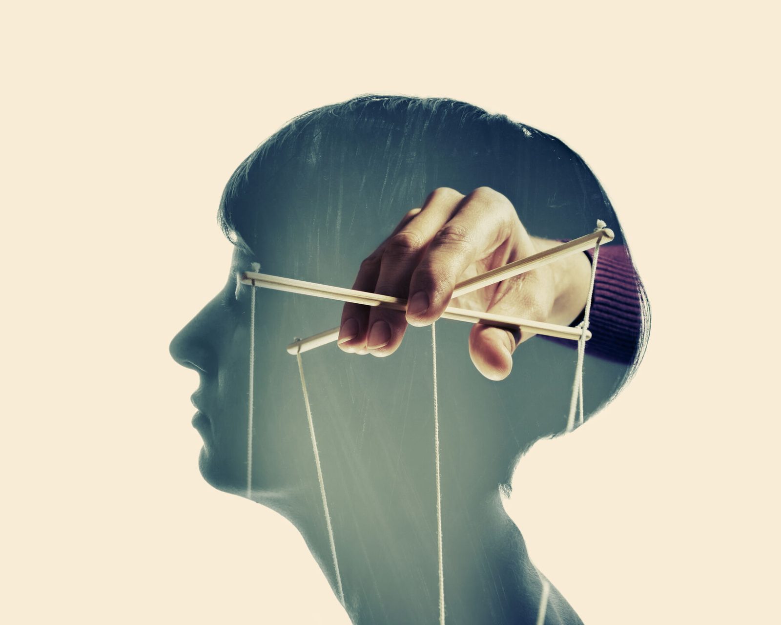 A hand working puppet strings inside a human head